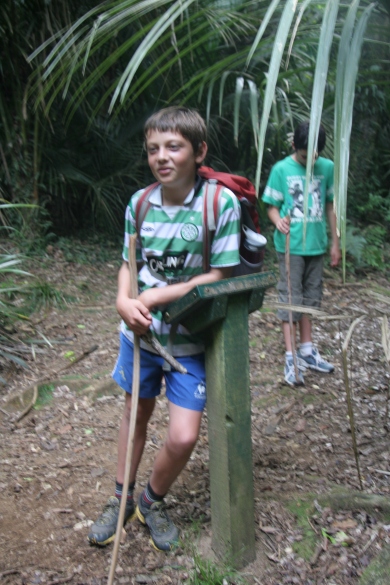 Boy leaning on signpost in bush